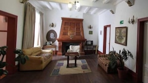 A spacious living room with a wooden fireplace, a sofa, a coffee table, and a fireplace rug. - Londres 35 Hotel (Santiago)