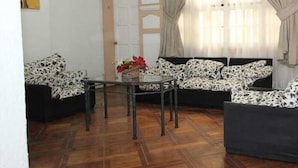 A living room with a sofa set, a coffee table, and a door. - Londres 35 Hotel (Santiago)