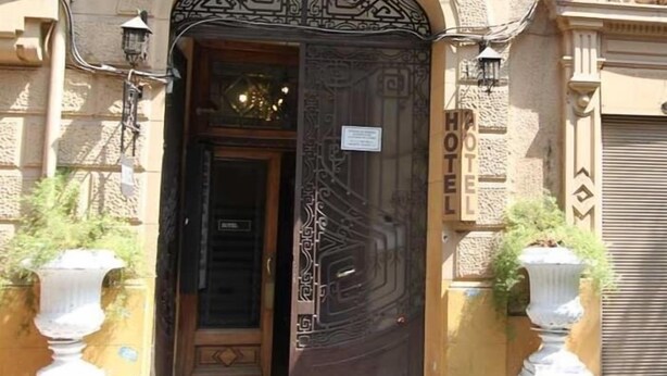 A hotel entrance with an ornate metal gate, a wooden door, and a sign indicating the hotel's name. - Londres 35 Hotel (Santiago)