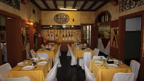 A restaurant with tables set for dining, featuring a central wall with decorative panels and a large emblem above the entrance. - Londres 35 Hotel (Santiago)