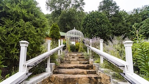 Eine Steintreppe mit weißen Geländern führt zu einem Gazebo.