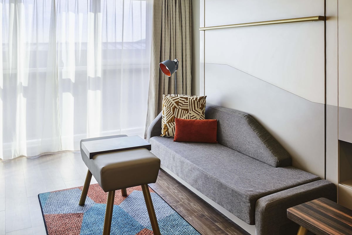 Een moderne woonkamer met een bank, een bijzettafeltje, een vloerlamp en een kussen met een patroon.