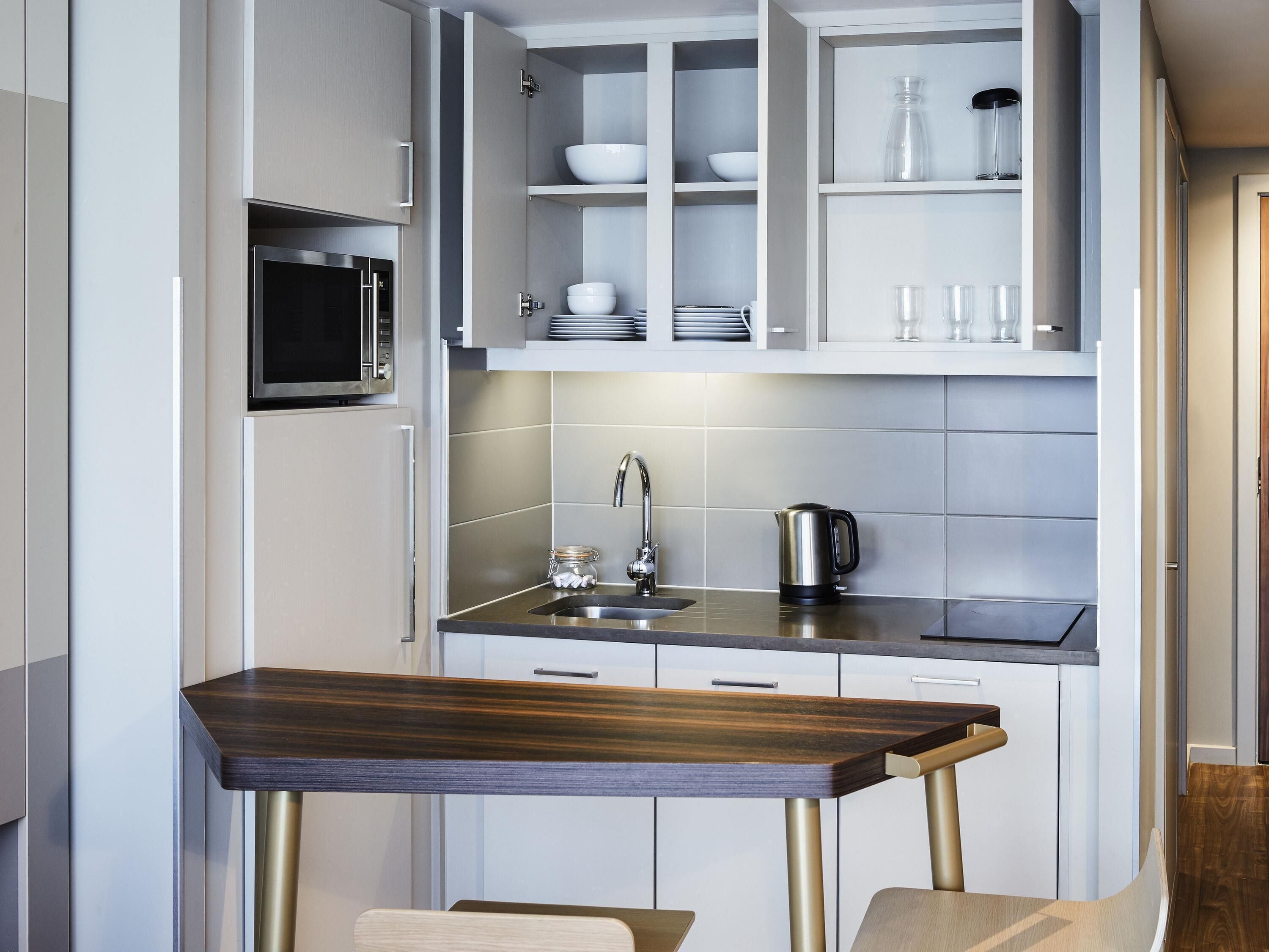 A modern kitchen with a built-in microwave, stainless steel sink, and a wooden dining table.