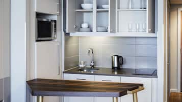 Una cocina moderna con microondas integrado, lavamanos de acero inoxidable y una mesa de comedor de madera.