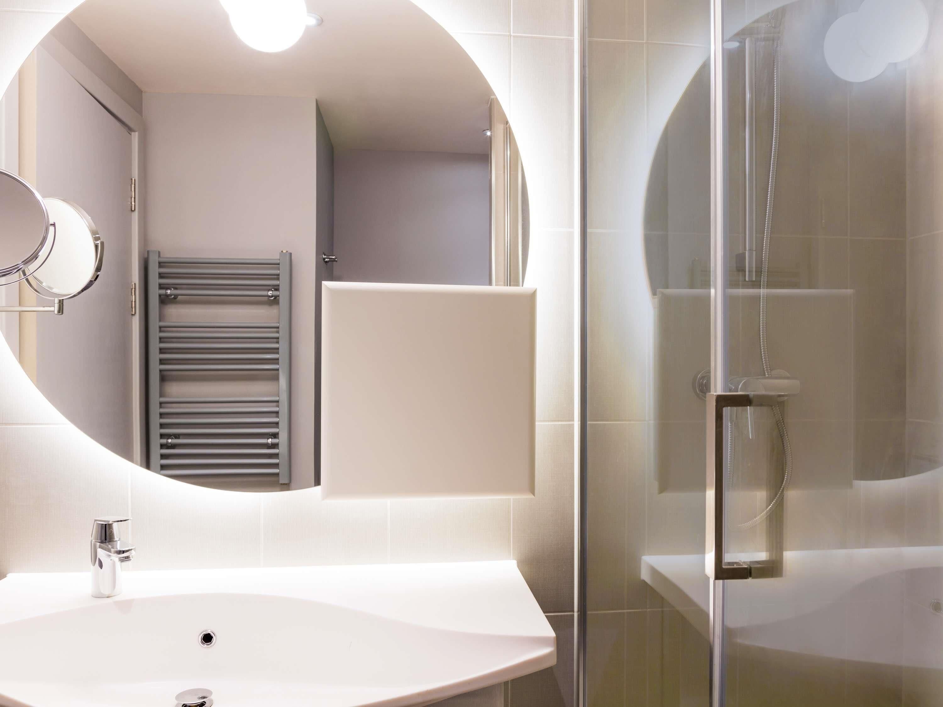 A modern bathroom with a freestanding sink, a glass-enclosed shower, and a towel rack.
