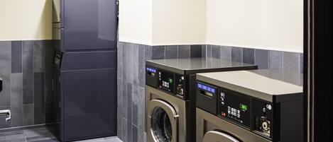 A laundry room with a refrigerator and two washing machines.
