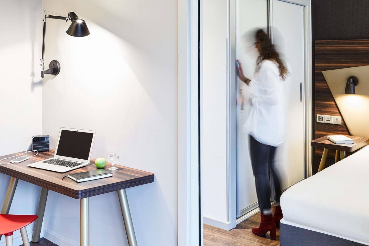 Una habitación de hotel con escritorio, computadora portátil y cama.