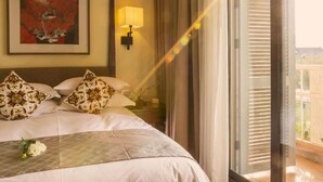 A hotel room with a bed, a painting, a lamp, and a view of the outdoors. - Narada Boutique Hotel (Wuhan)
