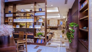 A modern hotel lobby with a central seating area, wooden bookshelves, and a decorative plant wall. - Narada Boutique Hotel (Wuhan)