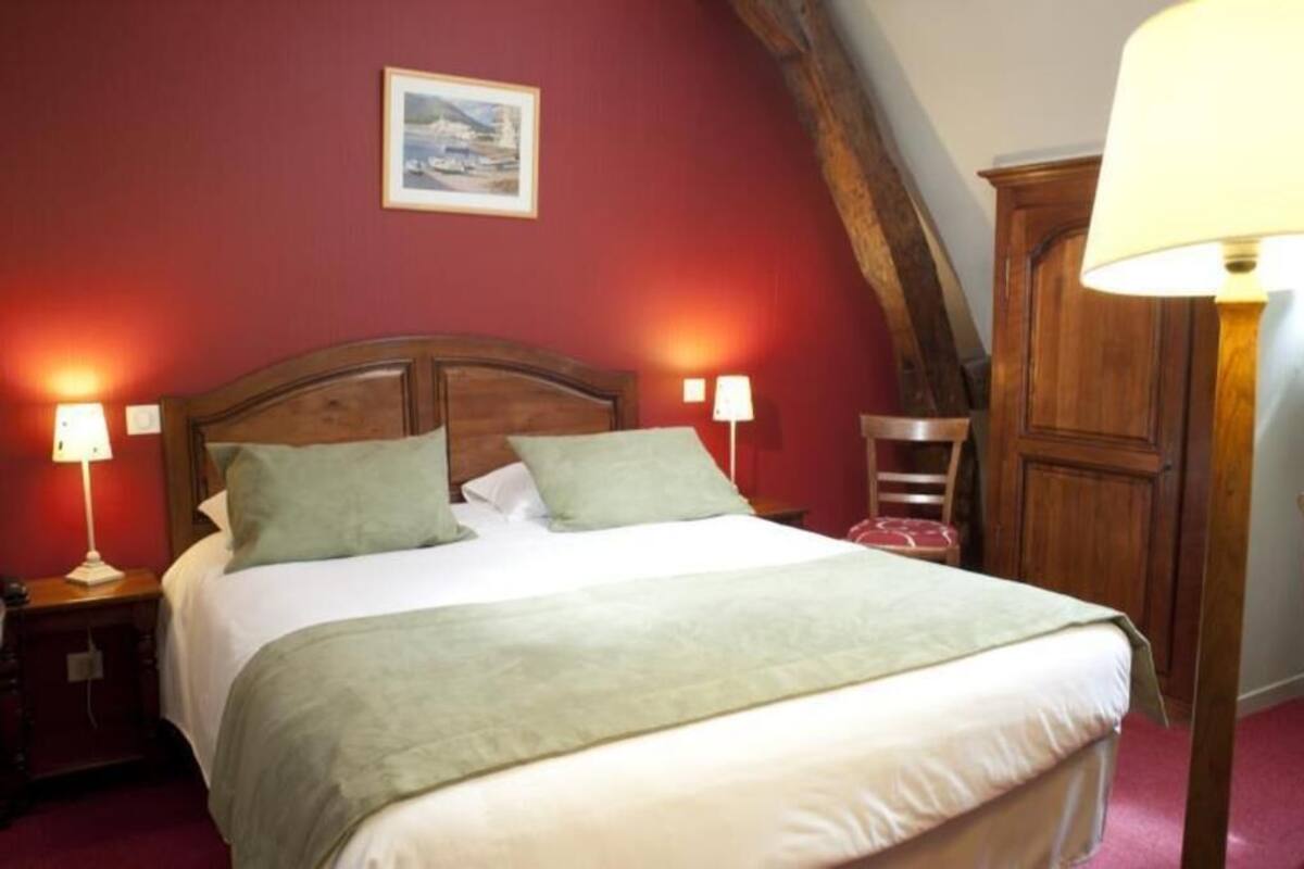 A bed with a wooden headboard, two bedside lamps, and a green throw blanket.