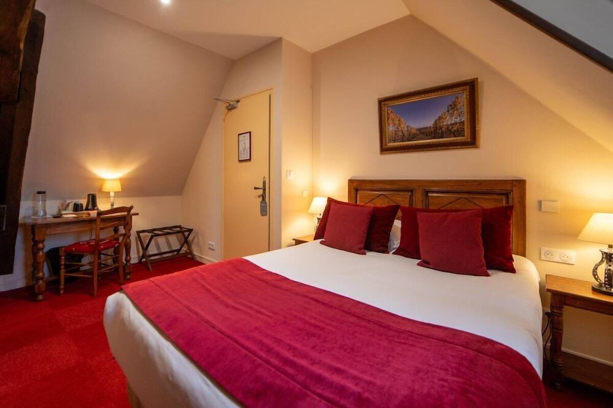 A bedroom with a large bed, a desk, and a chair.