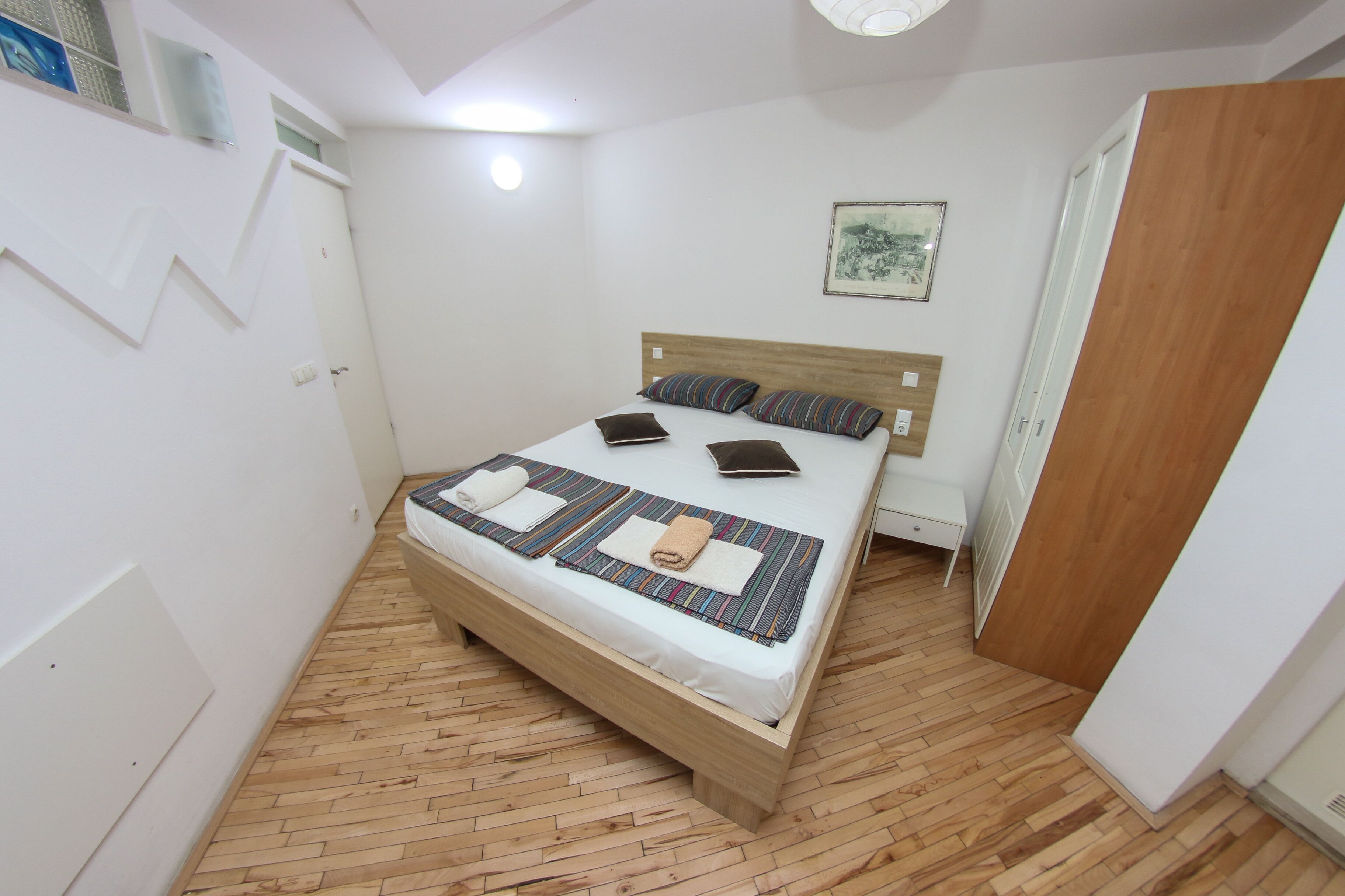 A neatly arranged bedroom with a wooden bed, a bedside table, and a small nightstand.