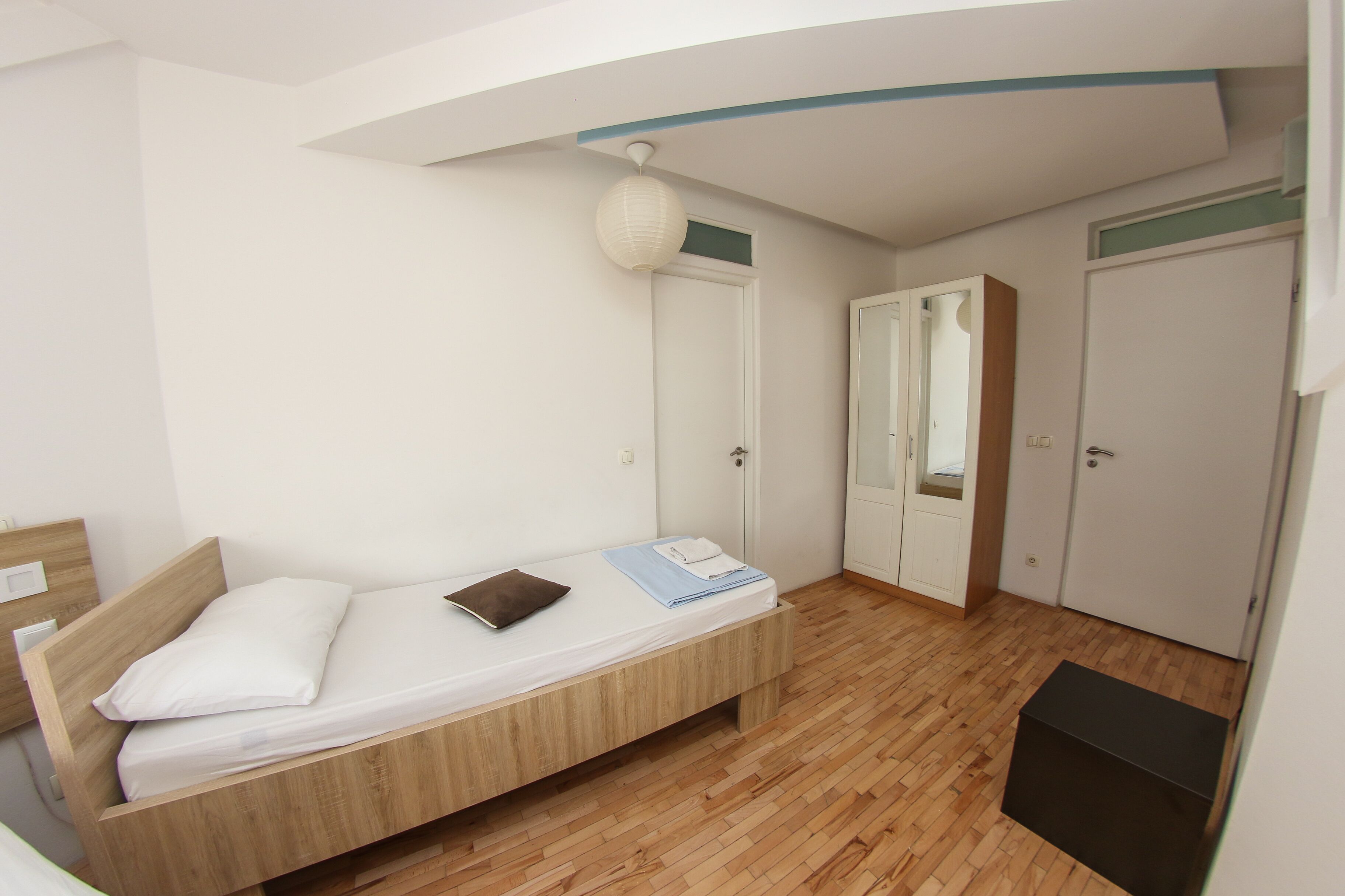 Une chambre à coucher avec un lit en bois, une table de chevet, une armoire et un miroir.
