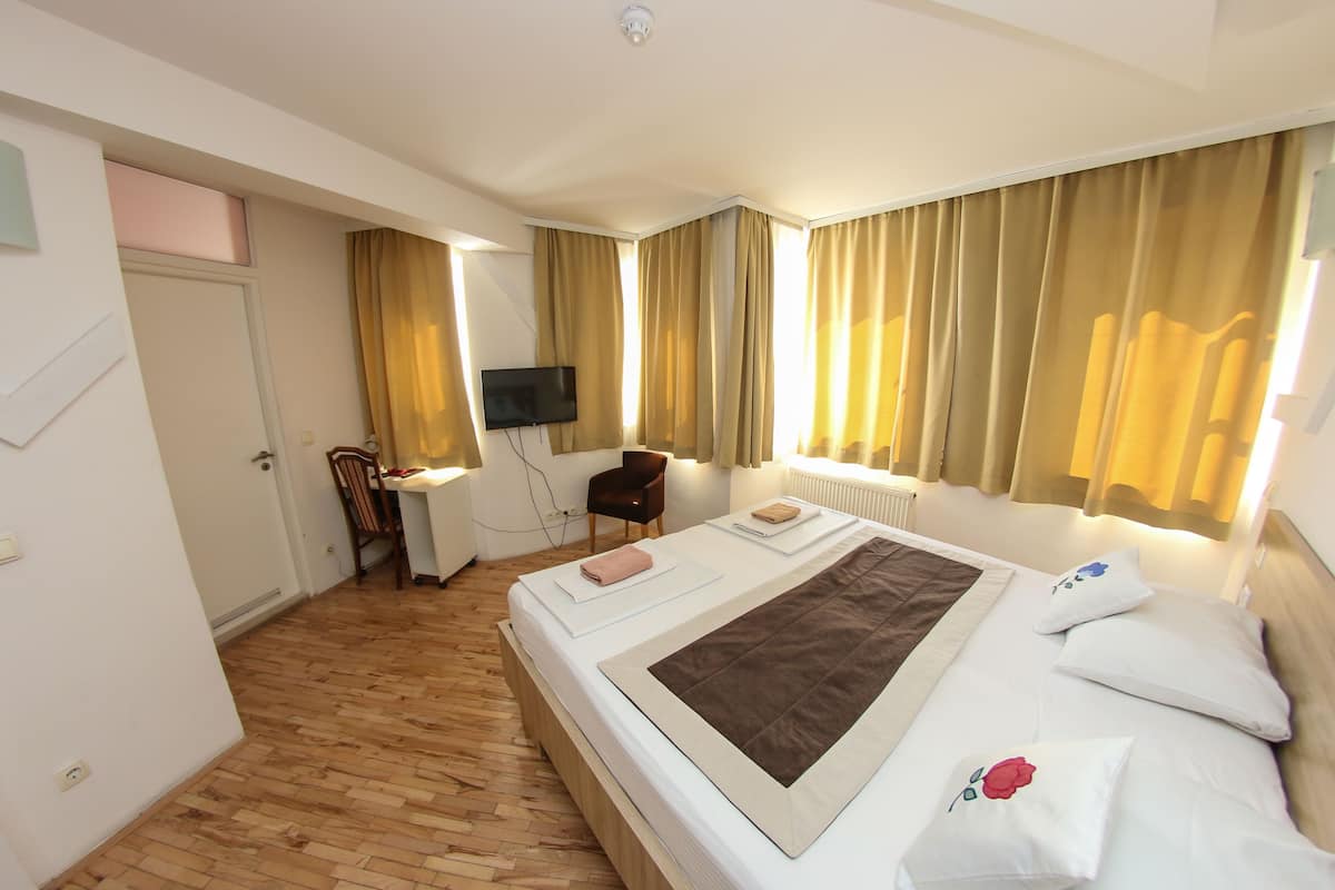 A hotel room with a bed, a desk, a chair, and a television.