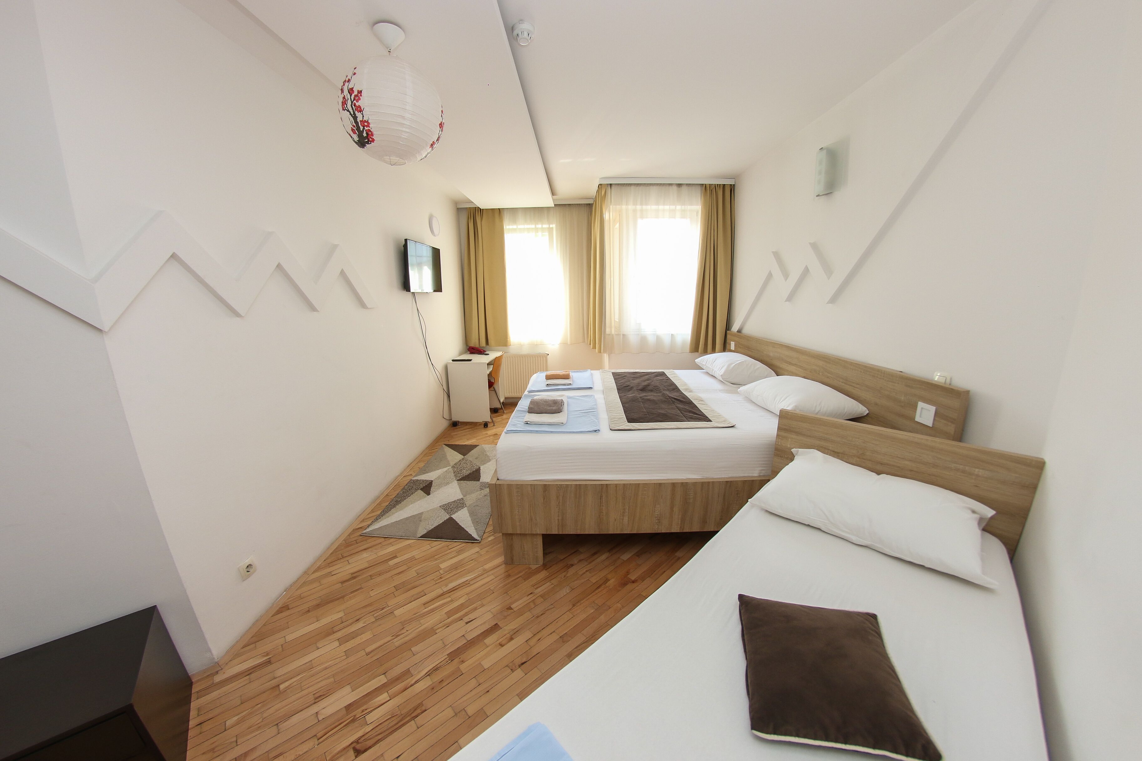 Una camera d'hotel con un letto, un comodino, una lampada e vista sull'esterno.