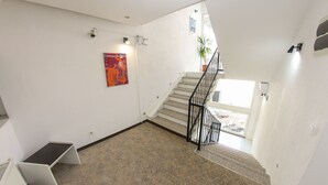 A staircase with a black railing, white walls, and a poster on the wall.