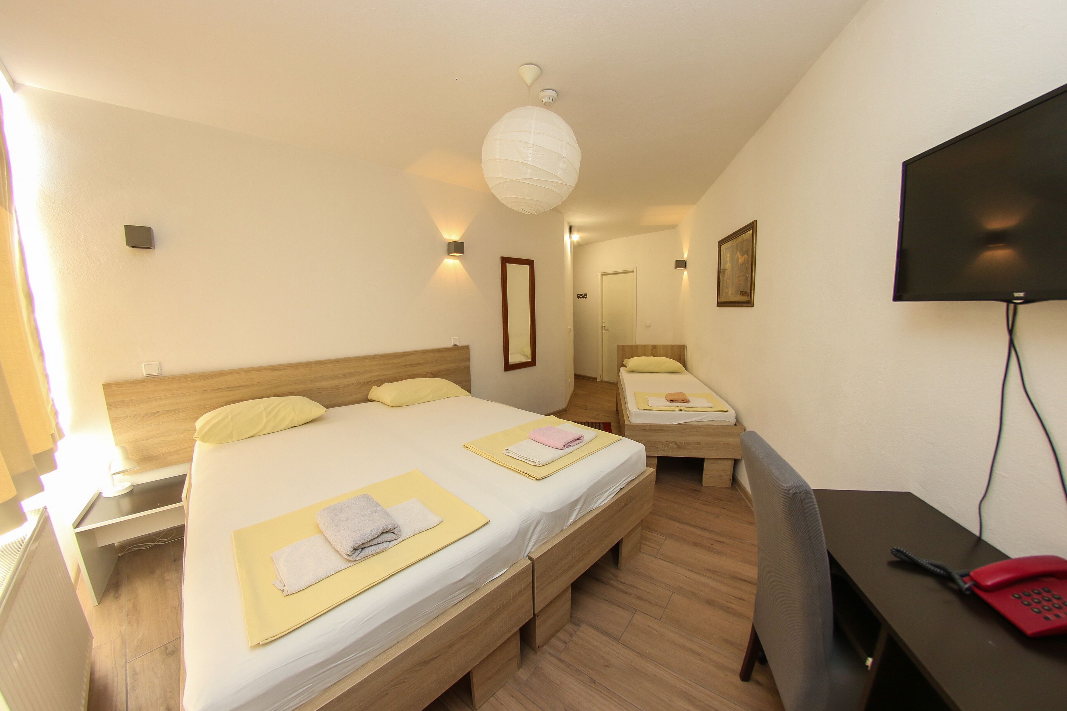 Habitación de hotel con dos camas, un escritorio, una silla, un televisor y un teléfono.