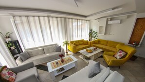 A modern living room with a white sofa, a yellow sofa, and a coffee table with magazines.