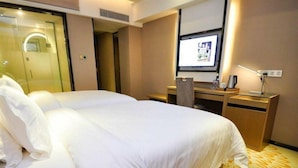Una habitación de hotel con una cama grande, un escritorio con computadora y un televisor en la pared.