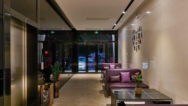 Un vestíbulo moderno con puertas de vidrio, zona de estar y plantas decorativas.