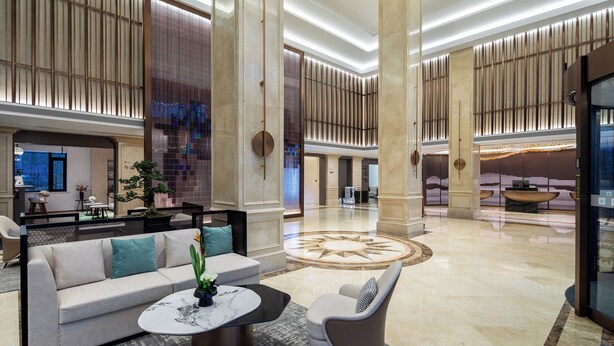 A spacious lobby with a central seating area, large pillars, and a decorative floor pattern. - Wyndham Garden Shanghai Pudong (Shanghai)