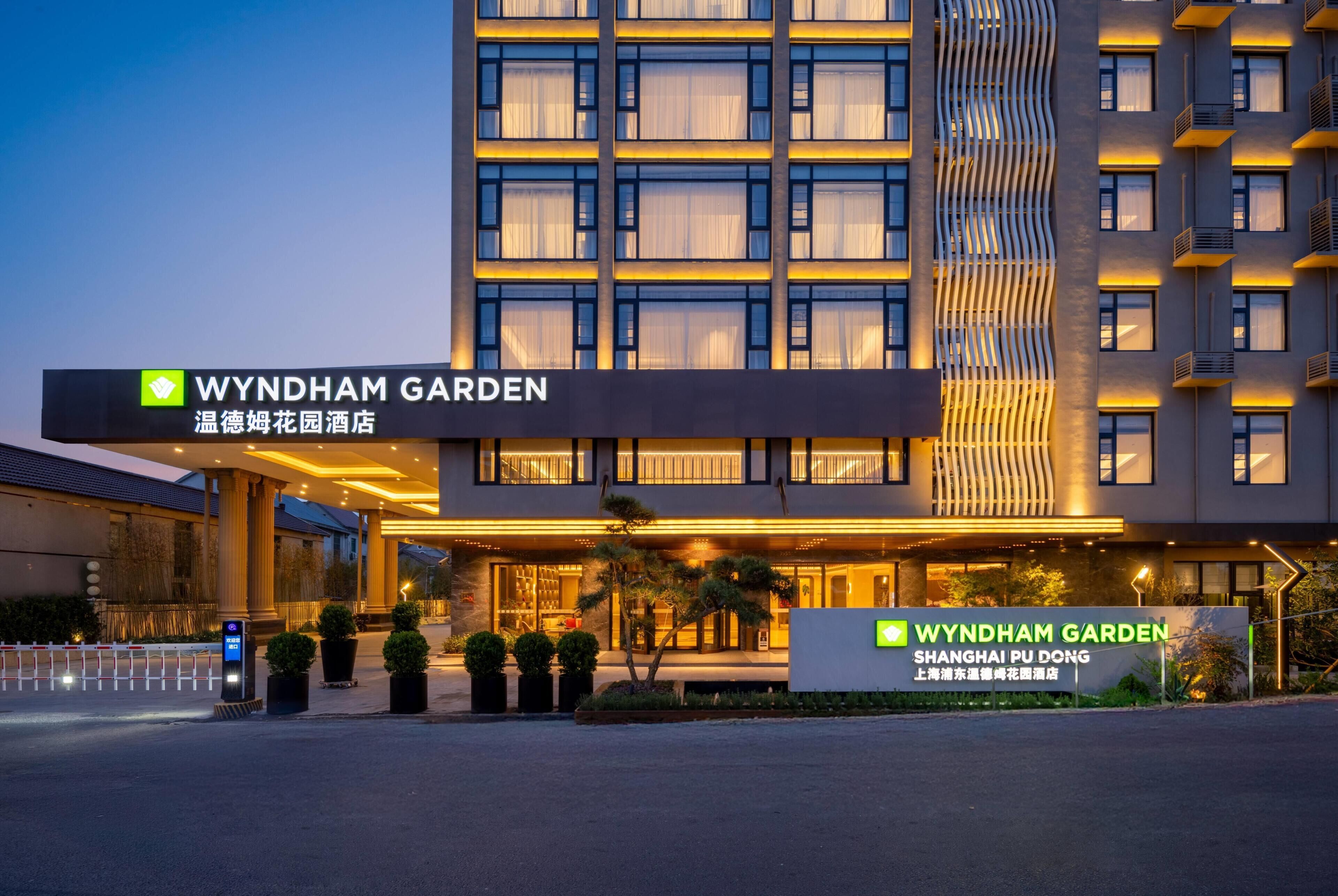 Ein Hotel mit moderner Fassade, Beschilderung mit 'WYNDHAM GARDEN' und einem gut beleuchteten Eingang.