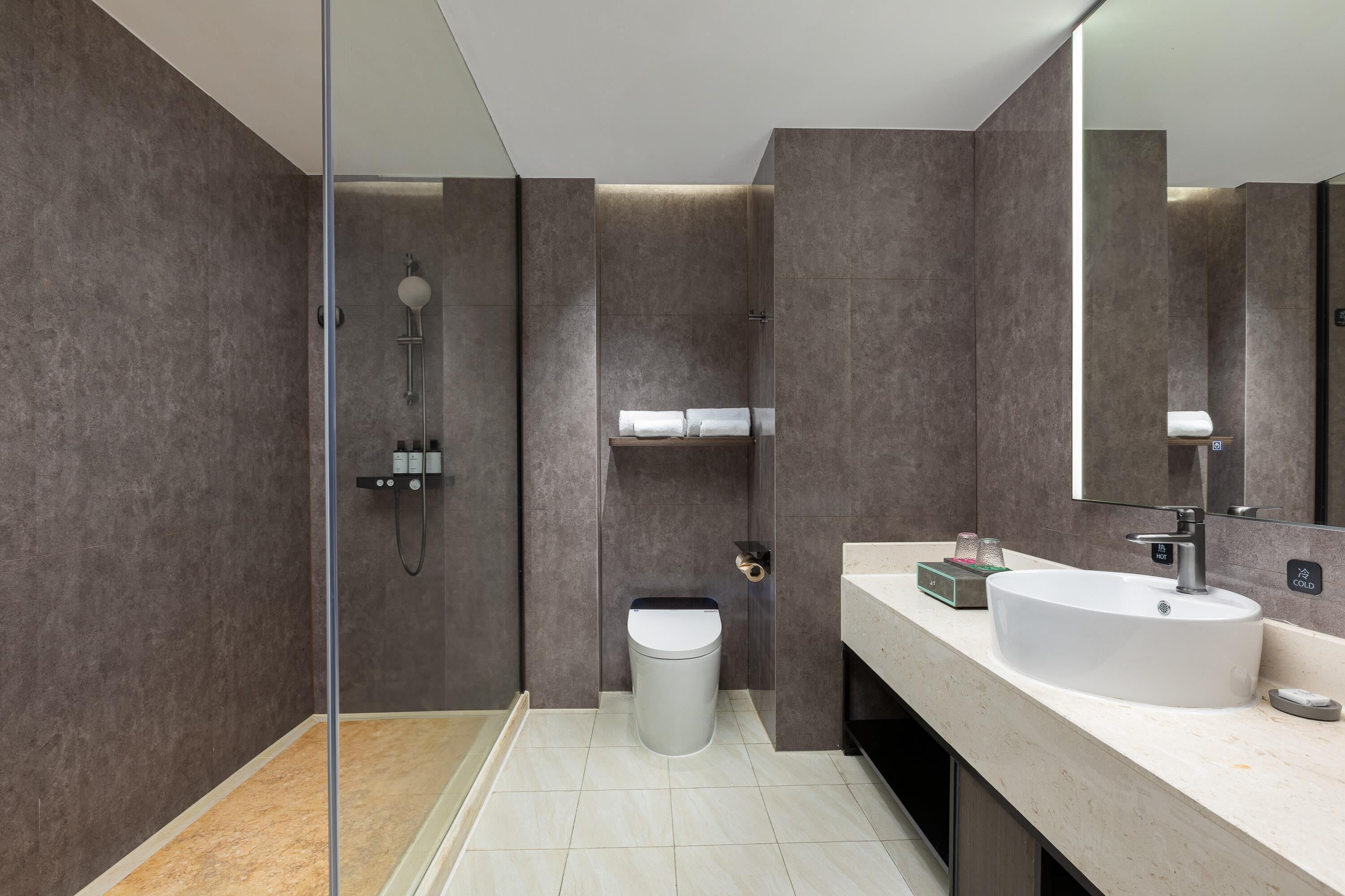 Un baño moderno con cabina de ducha de vidrio, un lavabo blanco y un espejo grande.