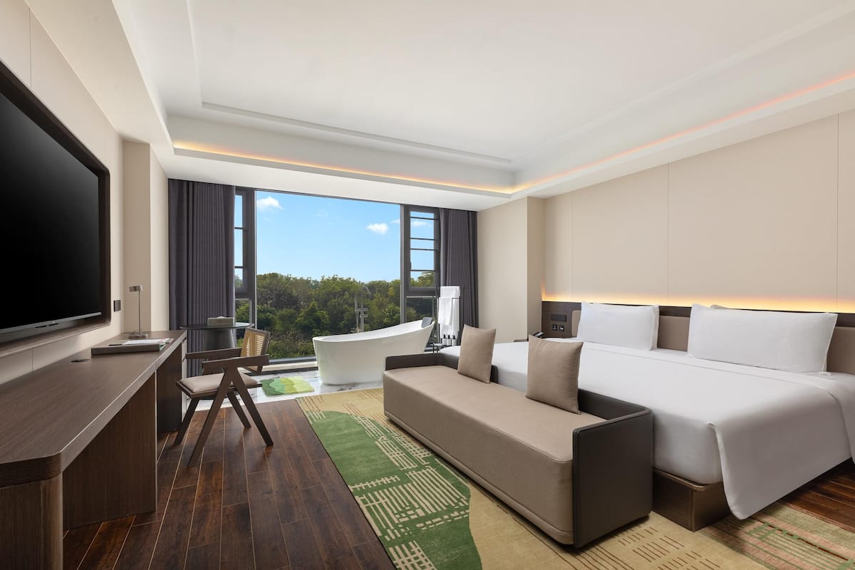 Une chambre d’hôtel moderne équipée d’un grand lit, d’un canapé, d’un bureau et d’une télévision.