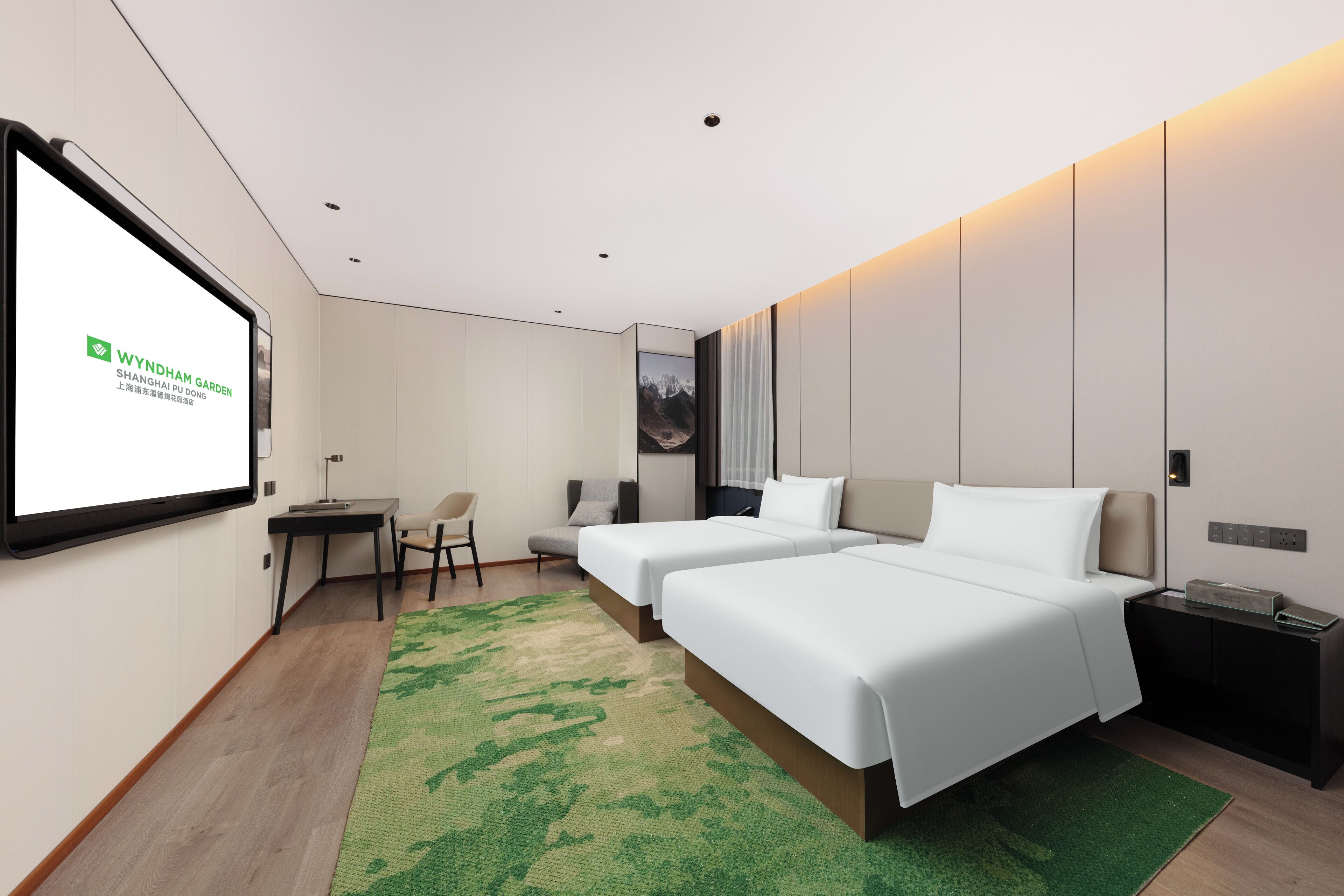 Une chambre d’hôtel moderne équipée de deux lits, d’un bureau, d’une chaise, d’un écran de télévision et d’une moquette verte.
