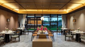 A spacious dining area with multiple tables and chairs, a central floral arrangement, and large windows offering a view of the outdoors. - Wyndham Garden Shanghai Pudong (Shanghai)