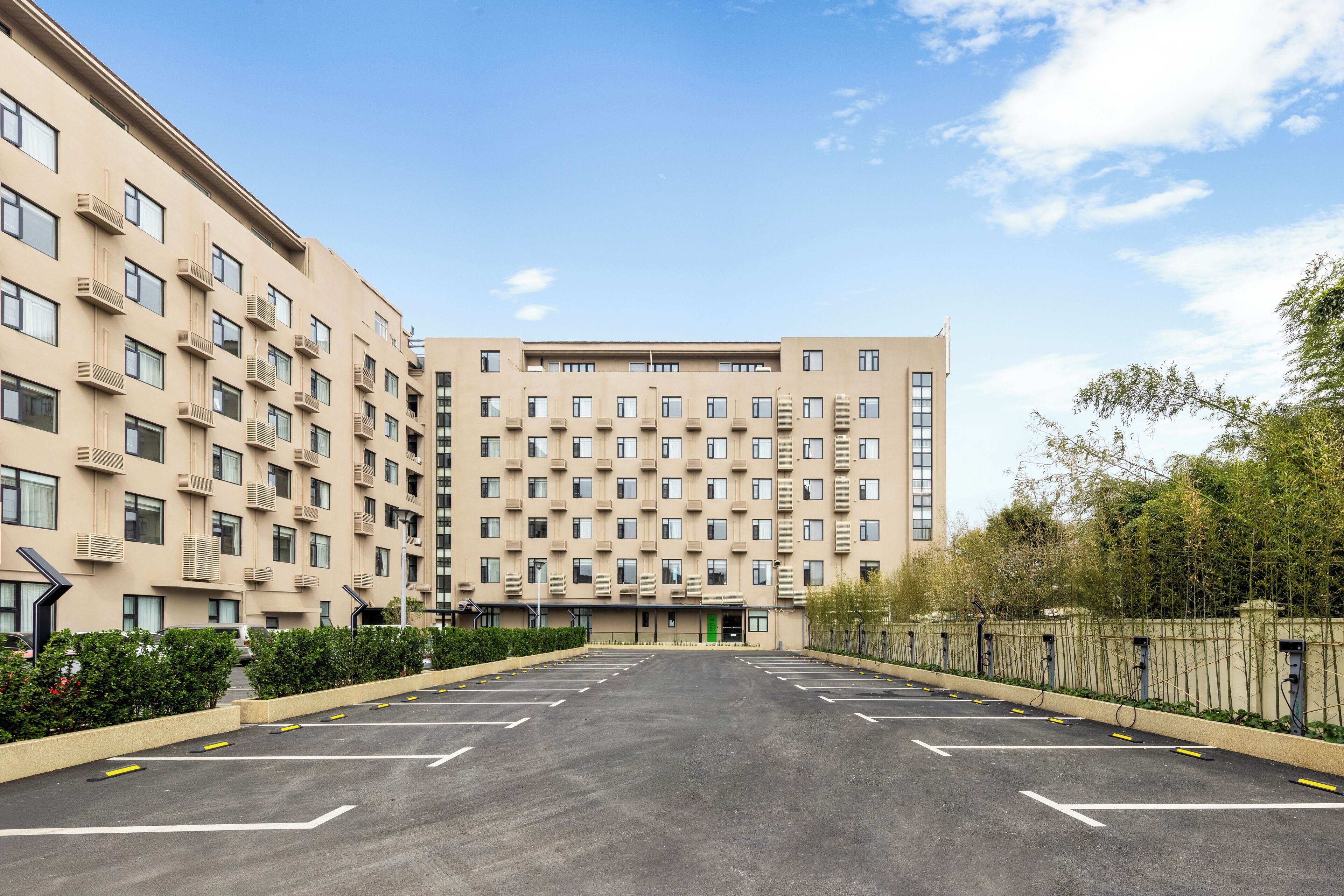 A multi-story hotel with a parking lot in front.