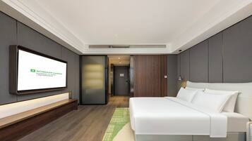 Una habitación de hotel moderna con una cama grande, un televisor de pantalla plana en la pared y un banco de madera.