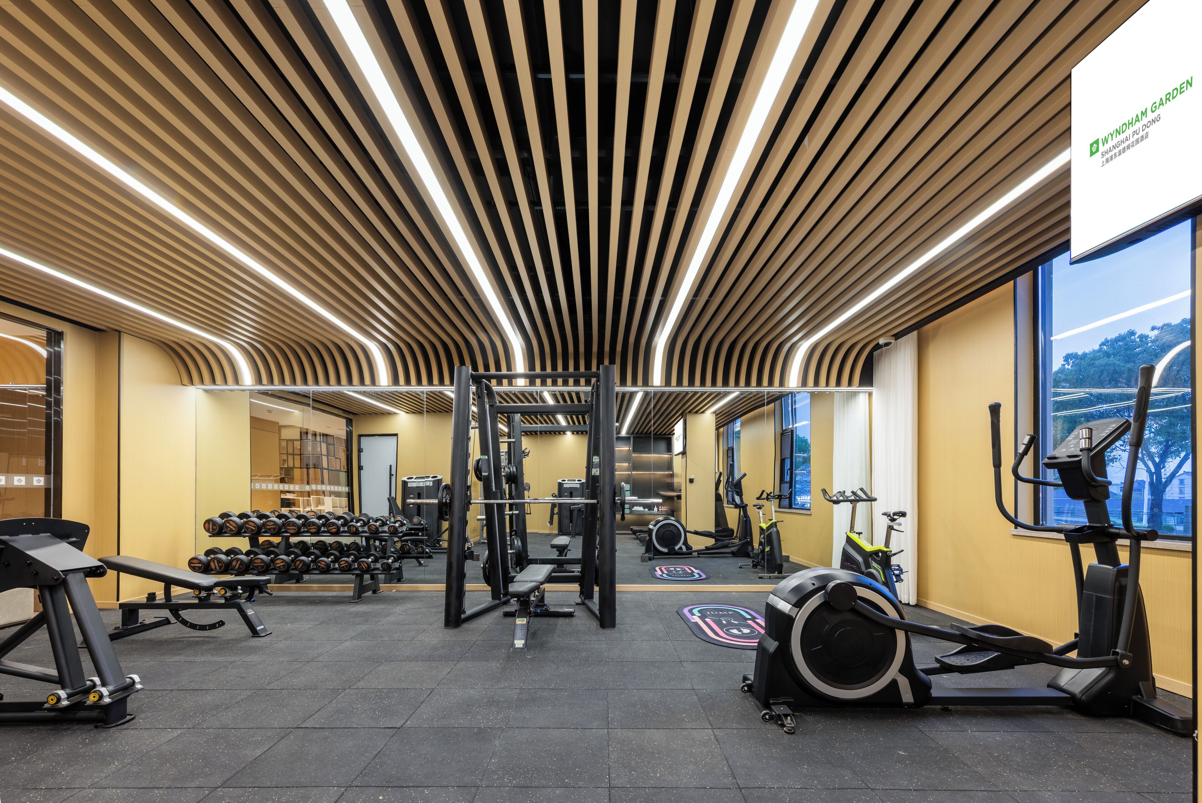 A gym with exercise equipment, a mirrored wall, and a large window with a view.