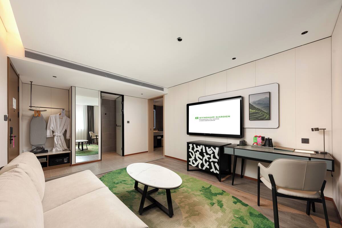 Une chambre d’hôtel moderne dotée d’un grand lit, d’un bureau, d’une télévision à écran plat et offrant une vue sur le jardin.