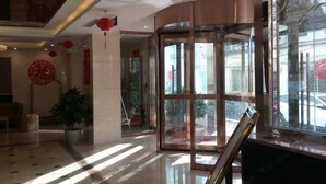 Eine moderne Hotellobby mit einer Drehtür, einem Blumentopf und Blick auf die Straße.
