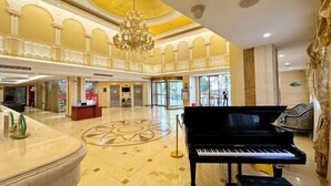 A grand lobby with a piano, a chandelier, and a reception desk. - Vienna Hotel (Shanghai)