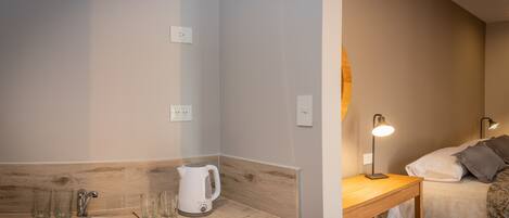 Un baño moderno con lavamanos, espejo y hervidor en la encimera.