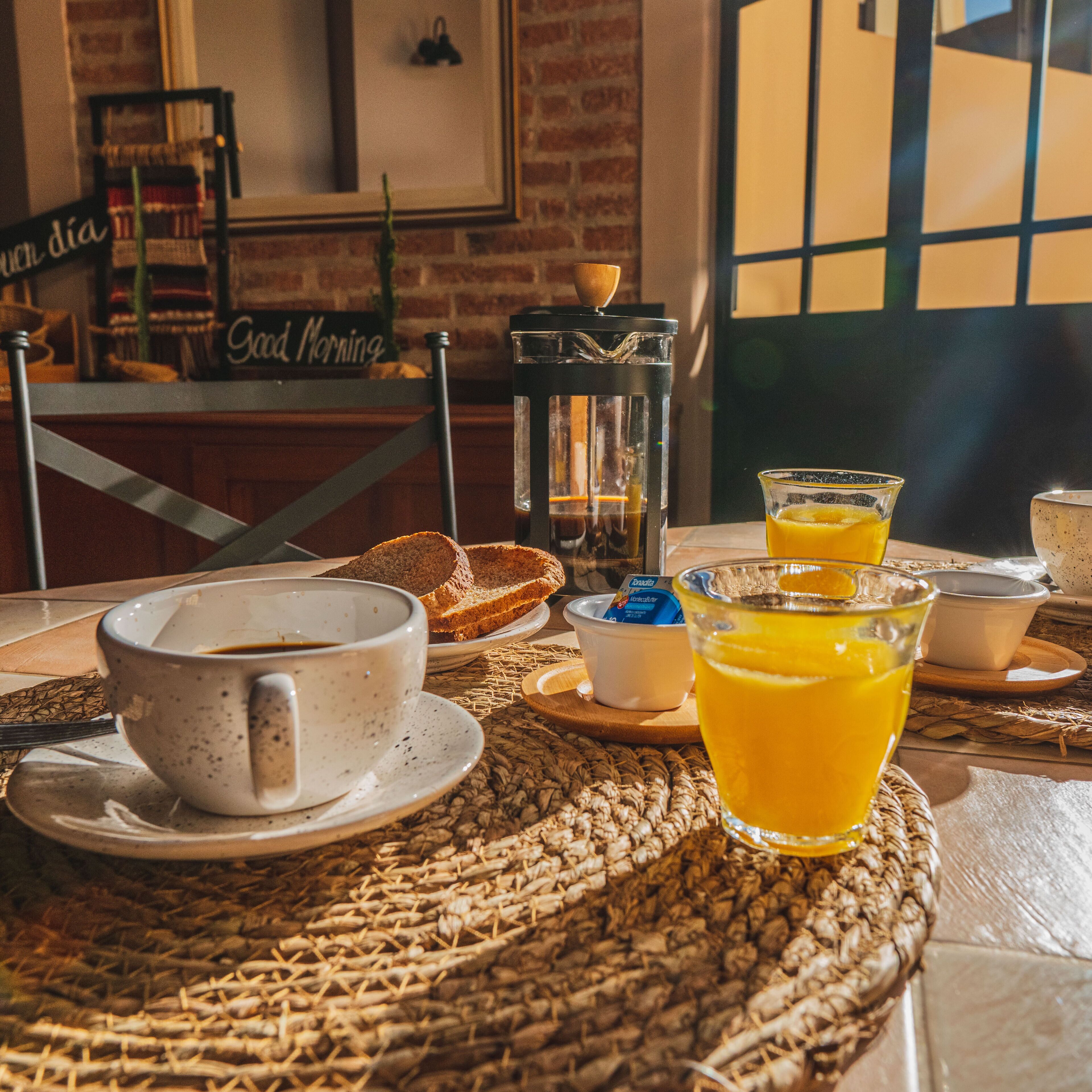 Ein Frühstückstisch mit einer Tasse Kaffee, Orangensaftgläsern und Brot.
