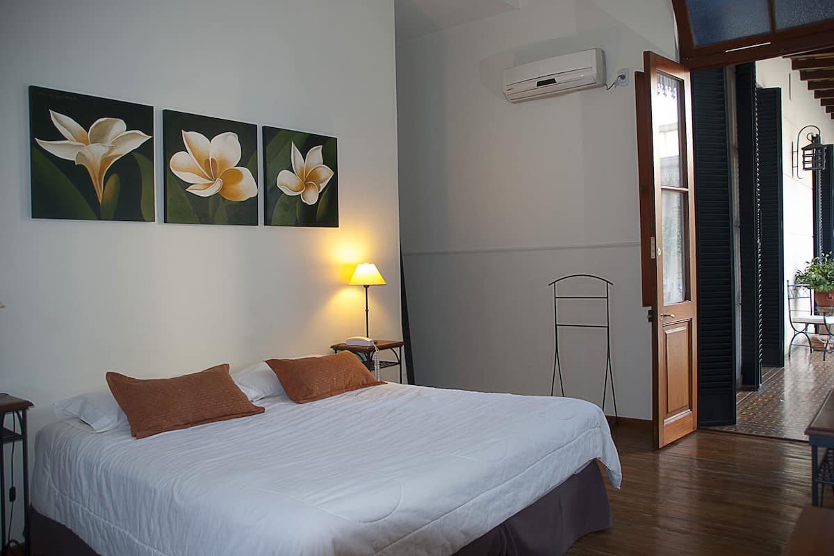 A hotel room with a bed, a nightstand, a lamp, and three wall-mounted flower paintings.