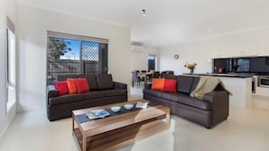 A modern living room with two sofas, a coffee table, and a kitchen area in the background. - Bradford Place (GLADSTONE PARK)