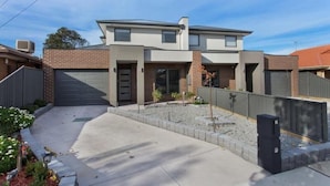 A modern two-story house with a garage, a landscaped front yard, and a clear sky. - Bradford Place (GLADSTONE PARK)