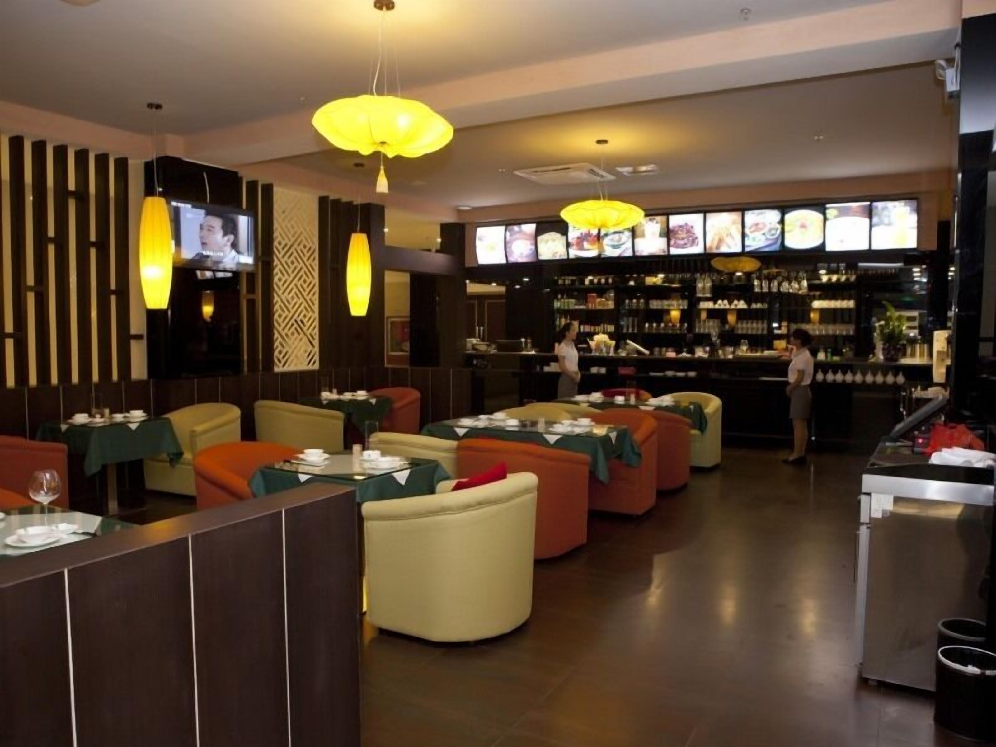 Un restaurante con mesas y sillas, una zona de bar y una pantalla de televisión mostrando comida.