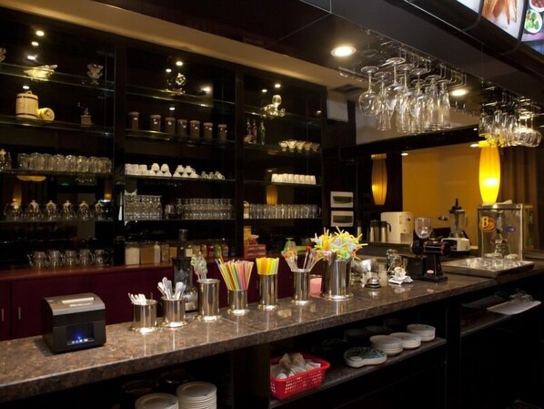 Un espace bar avec des étagères remplies de verres, une caisse enregistreuse et une machine à café.