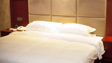 A hotel room with a large bed, a wooden headboard, and a nightstand with a telephone and a glass of water.