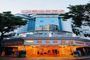 A Vienna Hotel with a modern glass facade, signage in multiple languages, and a well-lit entrance. - Vienna Hotel( Shenzhen Luohu Laojie Metro) (Shenzhen)