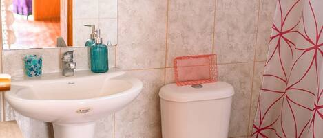 A bathroom with a white sink, a toilet, and a shower curtain.
