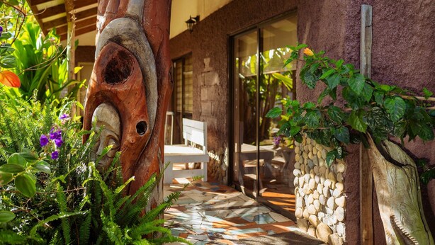 A wooden sculpture, a stone wall, and a tiled patio. - Cabañas Vaiora (Hanga Roa)