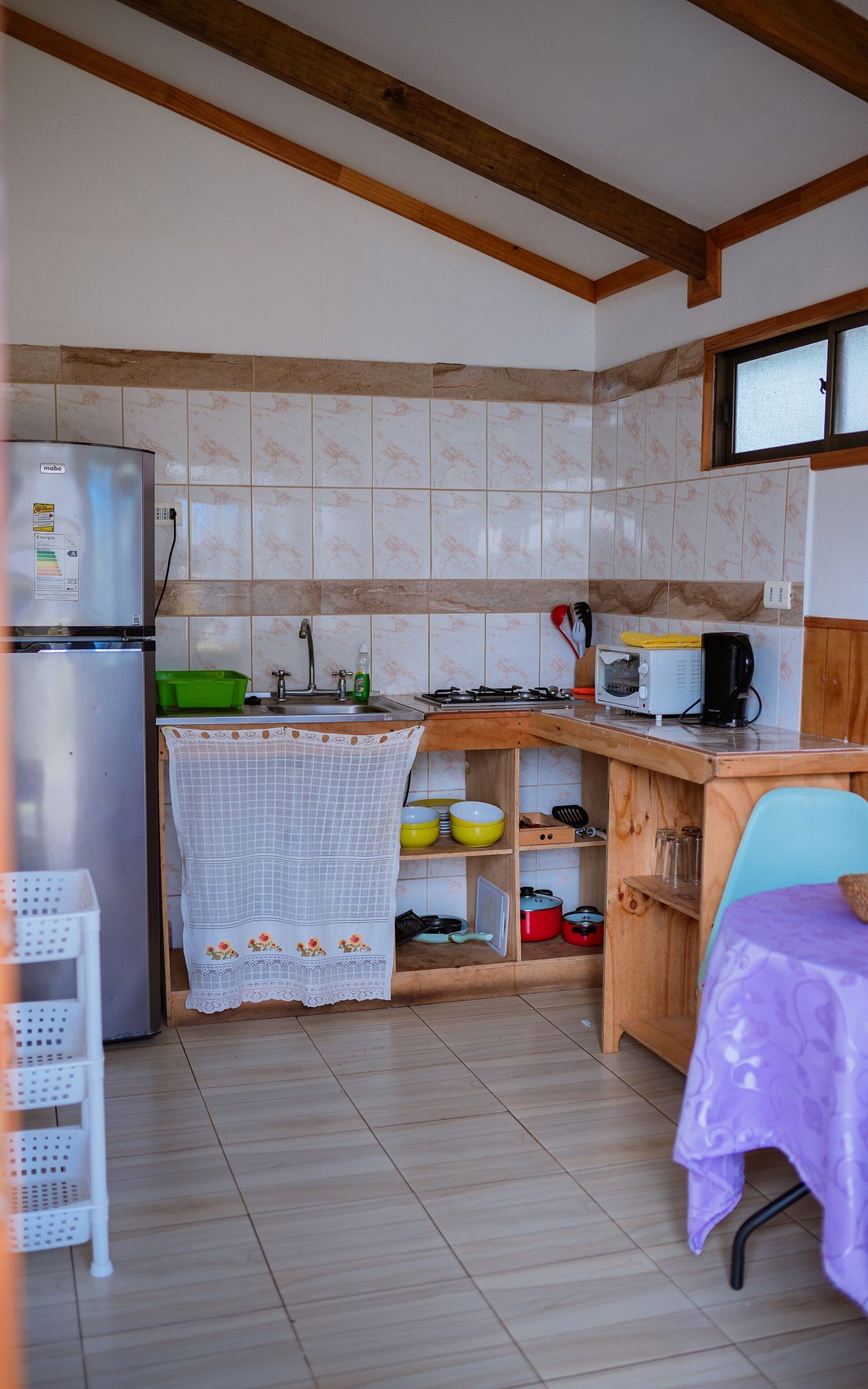 A compact kitchen with a refrigerator, a stove, a microwave, and a sink.