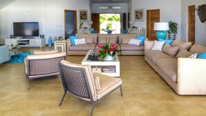 A spacious living room with a large sofa set, a coffee table with decorative items, and a television on a stand. - Villa Salamandra (Las Galeras)