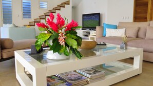 A modern living room with a glass coffee table, a sofa, a television, and a staircase. - Villa Salamandra (Las Galeras)